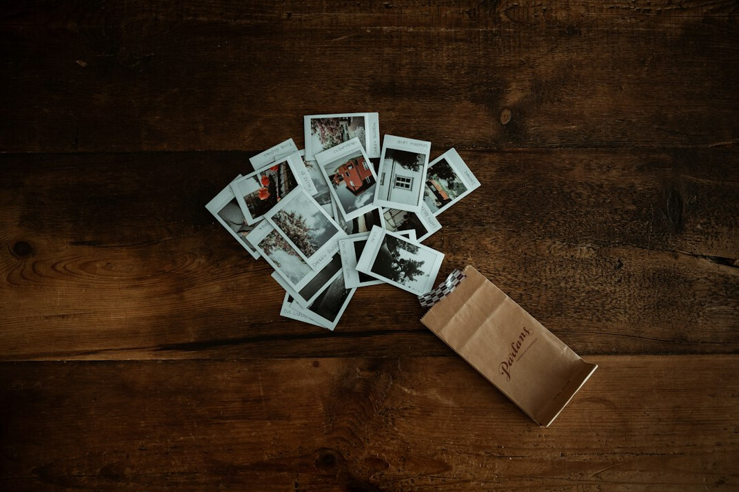 Photo prints and contact sheets spread over a table with a camera