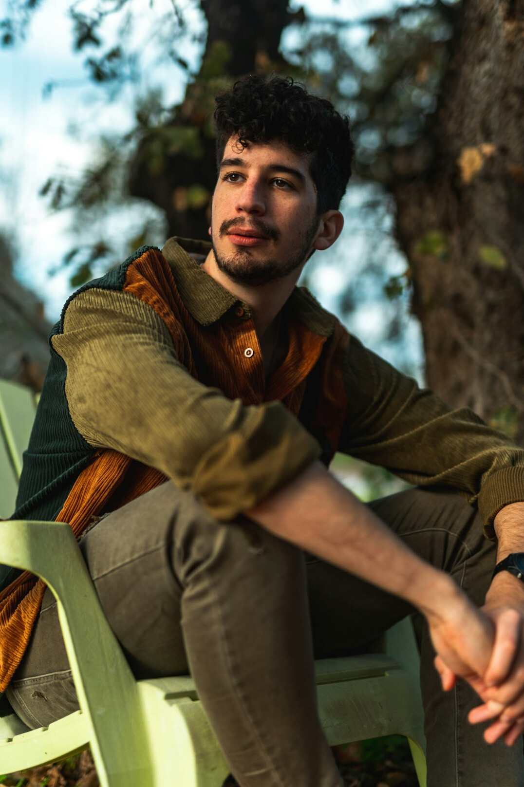 Portrait of a Latino man in his thirties with curly hair and a green sweater